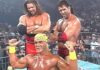 Three wrestlers standing in front of a crowd.