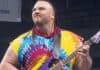 Man Mountain Rock, played by Darryl Peterson, wearing a tie-dye shirt and holding a purple electric guitar in a WWF ring in 1995